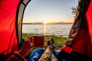 A man camping and watching the sunset from his tent-best tents for kayak camping